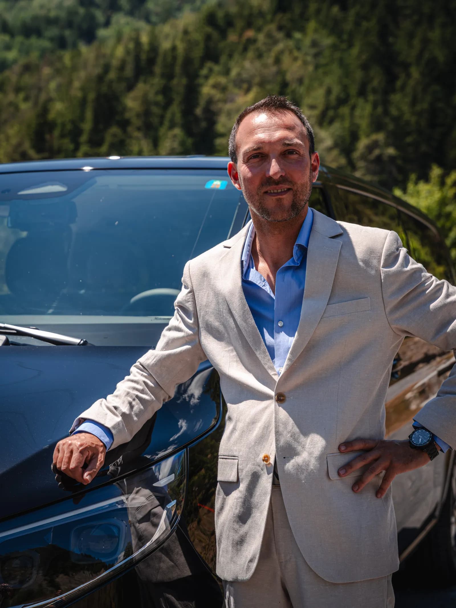 Julien Duret, founder of All in Taxi, in a suit in front of his Mercedes van in Crans-Montana